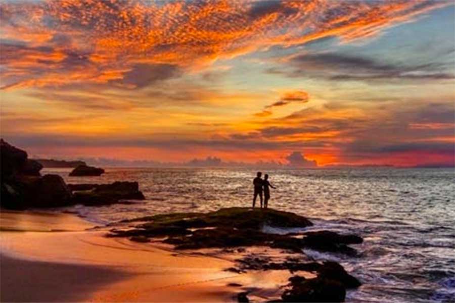 Two people on the beach at sunset